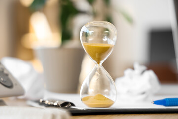 Hourglass on clipboard in office, closeup
