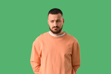 Apologetic young man on green background