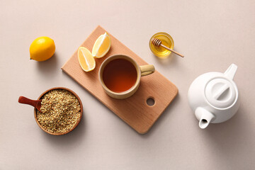 Cup and teapot of hot buckwheat tea with lemon and bowl of honey on grey background