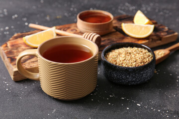 Cup of hot buckwheat tea with lemon and bowl of honey on black background