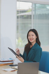Obraz premium Asian professional businesswoman working on tablet computer in a corporate office