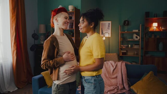 Woman caresses belly of pregnant partner feeling movements of baby