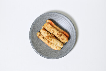 Traditional Indonesian Food, known as otak-otak ikan. Made from fish and served on the grey or gray plate. Top view, flat lay. Isolated on white background.