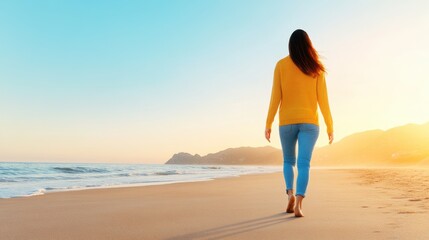 A woman is walking on the beach at sunset