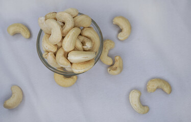 Cashew nuts, raw cashews in a bowl on linen fabric. Seeds of shelled fruits of cashew tree Anacardium occidentale. Used as snack nuts, and in recipes, or processed into cashew butter or cheese.