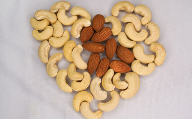 Almonds, cashews and pistachios nuts scattered on a white background in the shape of a heart top view.