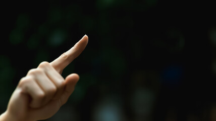 Guiding Hand: A Close-up of a finger pointing towards a dark, blurred background, suggesting direction, guidance, or a call to action.
