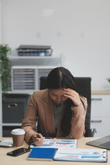 Portrait of tired young business Asian woman work with documents tax laptop computer in office....