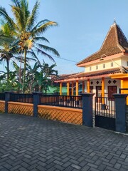 Charming Javanese house with a pyramid-shaped roof and tropical trees. Indonesian cultural heritage.