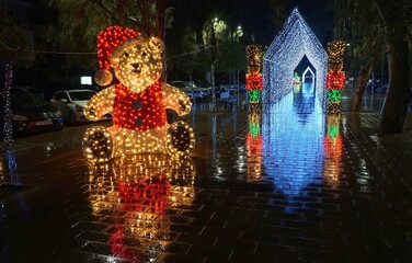 Rainy Christmas. Luminous Santa bear statue and tunnel with Nutcrackers under the rain