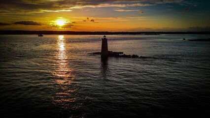 Sunset over ocean with lighthouse reflection.