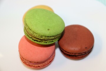 Close-up of green and pink macarons on a white plate.