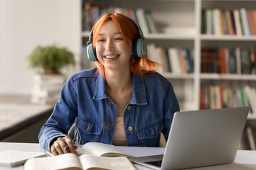 Happy remote student. Smiling trendy looking teen girl spend learning time at college library...