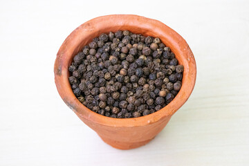 Black pepper (Piper nigrum) in an earthenware clay cup.