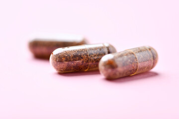 Siberian ginseng (Eleutherococcus senticosus) capsules on bright background. Soft focus. Close up. Copy space