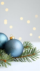 Blue Christmas ornaments on pine branch, bokeh lights background; holiday greeting card.
