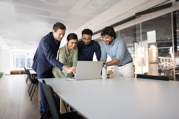 Diverse creative team working on online project together, meeting at laptop in modern office open,...