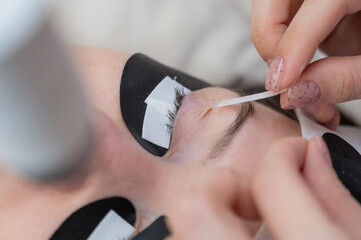 A specialist glues a client's drooping eyelid before eyelash extensions. 