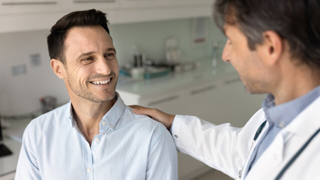Happy male patient getting support, congratulation, shoulder touch, good news from gp doctor, smiling, laughing, visiting practitioner for examination, medical checkup. Banner shot