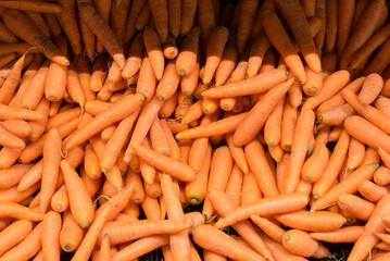 Group of carrots stacked on a supermarket shelf.