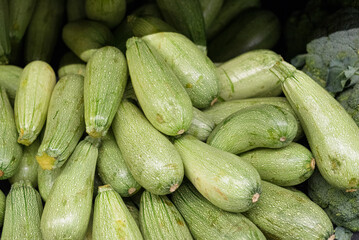 Group of zucchini stacked on a supermarket shelf.