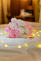 romantic hotel room scene with a beautiful bouquet of flowers placed elegantly on the bed. The soft petals of the flowers are surrounded by twinkling string lights, creating a warm and inviting