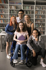 Inclusion and diversity. Vertical shot happy diverse polyethnic students group posing for portrait. Smiling teen female on wheelchair look at camera together with friendly supportive mates at library