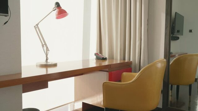 A contemporary workspace featuring a sleek desk, stylish lamp, and cozy seating. The design incorporates natural light and minimalistic decor, ideal for productivity and comfort.