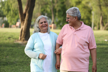 Indian happy senior beautiful couple embracing tohether and looking romantic and close together in garden