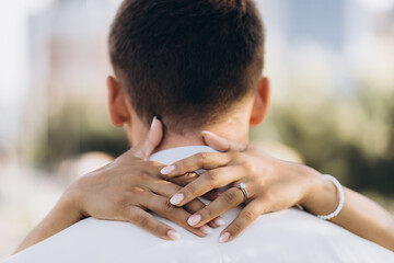The bride's hands hug the groom's neck