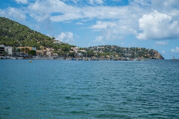 Coastal town harbor with boats and green hills