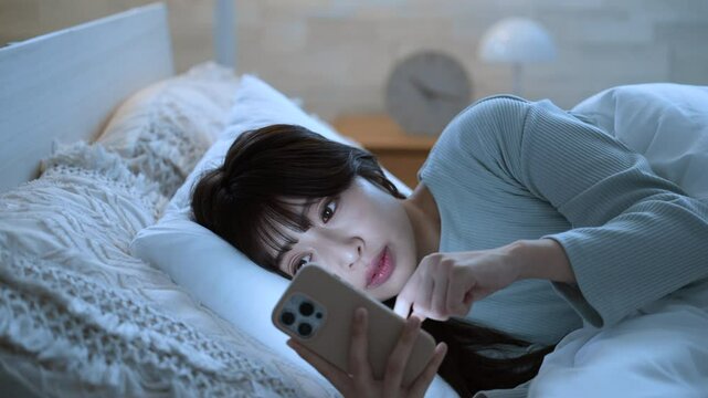 夜中にスマホを見て睡眠が足りず寝不足になってしまう女性のクローズアップでタップする動画　青色系