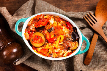 Provence roasted vegetables, baked vegetables in a baking dish on a wooden table