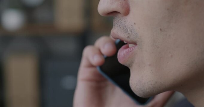 Close-up of male mouth speaking on mobile phone against blurred office background. Professional communication and modern technology concept.