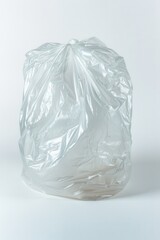 Obraz premium A crumpled, translucent plastic trash bag sits on a white background; its texture and light reflections are clearly visible, highlighting its form and the subtle shadows it casts.