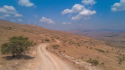 Fototapeta premium Scenic Wind Turbines Landscape Along Curved Dirt Road Under Clouds