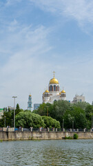 Fototapeta premium Central city pond in Yekaterinburg, Russia. Church on Blood in Honour of All Saints Resplendent in the Russian Land on embankment. Church in honor of Ascension of Lord. Vertical image