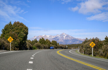 Road narrows on left road sign on Desert road. Mount Ruapehu in the distance. New Zealand.