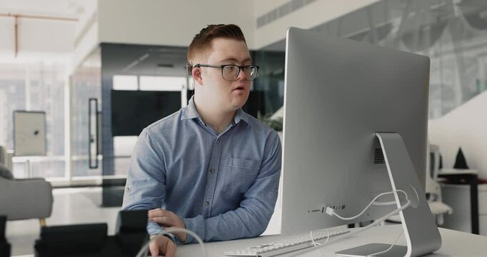 Man with Down syndrome using PC working in office, organize, analyze data in spreadsheets, managing schedules, responding to emails, or prepare documents and reports, browsing internet for information