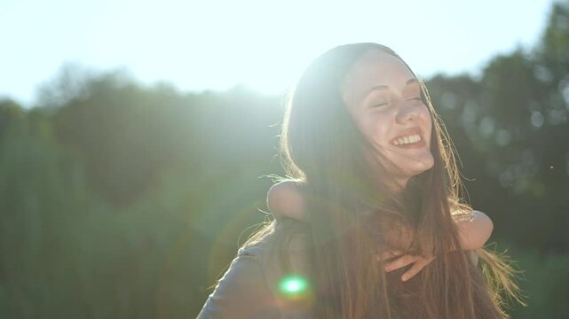 Mother giving piggyback ride to child outdoors. Happy child laughing while riding on mother back. Joyful playtime in nature. Mother and child piggyback fun. Active family moment outdoors in park
