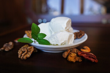 The ice cream, garnished with a fresh mint leaf and large walnuts, melts on a white dessert plate.