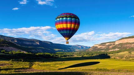 Obraz premium Colorful hot air balloon soaring over a scenic valley landscape.