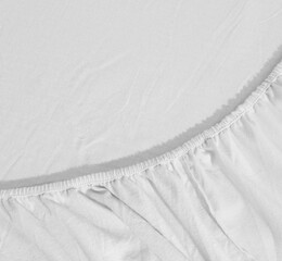 White cotton fitted sheet with elastic band bed corner, Bed corner on the bed close up photo, Flat sheet or bed cover