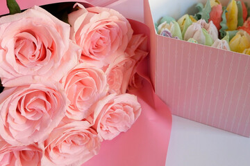 Huge bouquet of pink roses and box filled with colored meringue cookies as flowers. Gift box of Zefir marshmallow and flowers.
