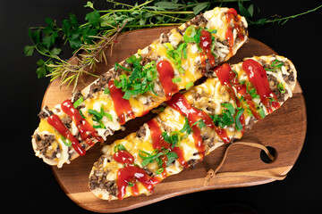 Toasted open-face sandwich made of a sliced baguette  topped with white mushrooms, cheese and ketchup, zapiekanki