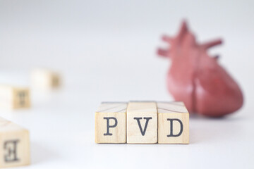 Peripheral artery disease acronym. PVD abbreviation written on wooden cubes isolated with heart on...