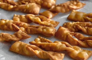 chrupiące smażone faworki leżące na ręczniku papierowym,  tradycja na tłusty czwartek, pysze domowe faworki, chrusty 