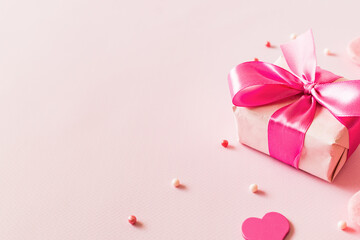 Pink hearts and gift box with ribbon on a light pink background