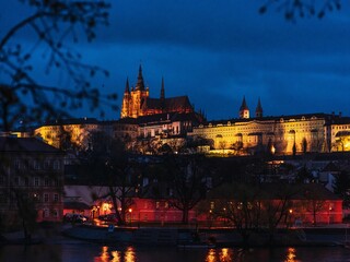 Obraz premium Prague Castle illuminated at night with reflections on the Vltava River.