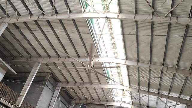 HVLS big fan on ceiling under the old metal curve roof structure of temple building, low angle view of big hvls fan. HVLS  fan on ceiling.